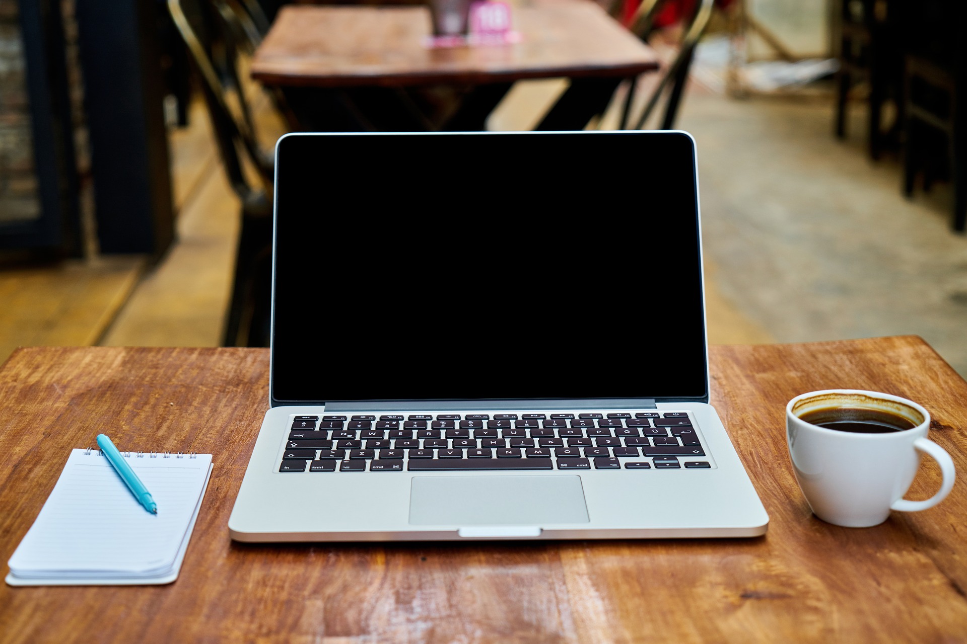 scrivania con laptop blocco note penna e caffè